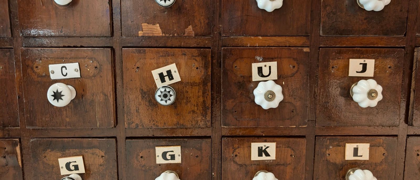 Ein alter Apothekerschrank mit vielen kleinen, einzeln beschrifteten Schubladen und Porzellanknäufen.